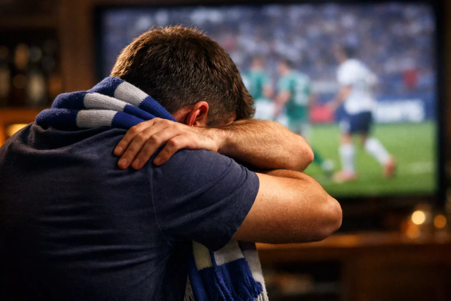 Persona viendo partido de fútbol mientras usa smartphone